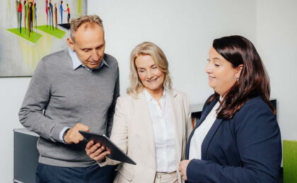 Annette Wodzak-Littig zeigt Matthias Littig und Franziska Nützel ein Dokument auf dem iPad.